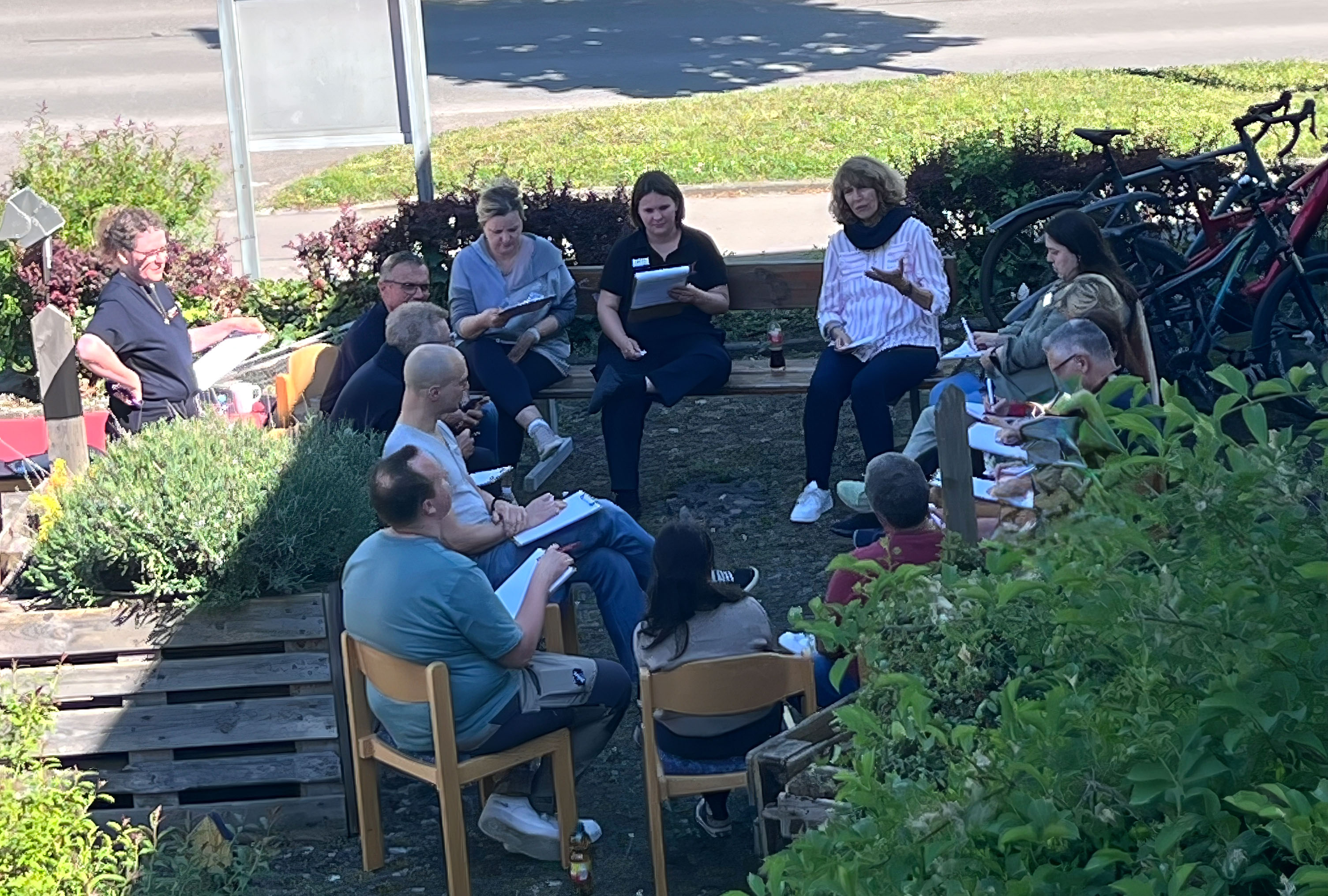 Auf dem Bild sind Teilnehmende bei der Gruppenarbeit im Freien zu sehen.  im Garteniche Helferinnen und Helfer aus den Bereitschaften Eningen und Pfullingen sowie Fahrzeuge des Bevölkerung- und Katastrophenschutzes zu sehen.