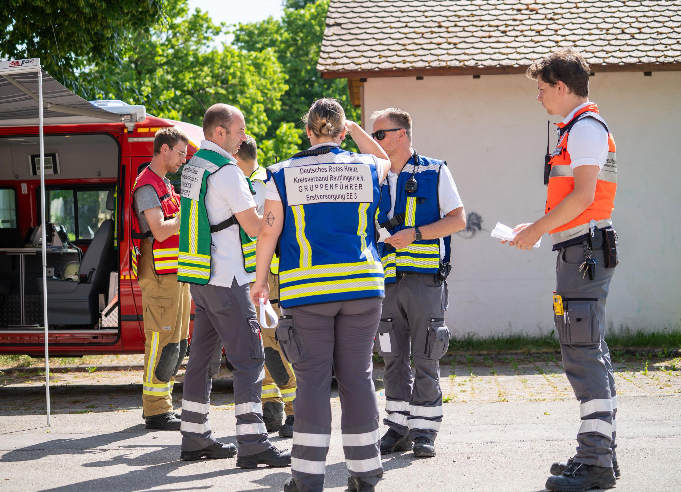 Die Führungskräfte besprechen sich vor einem Einsatzfahrzeug.