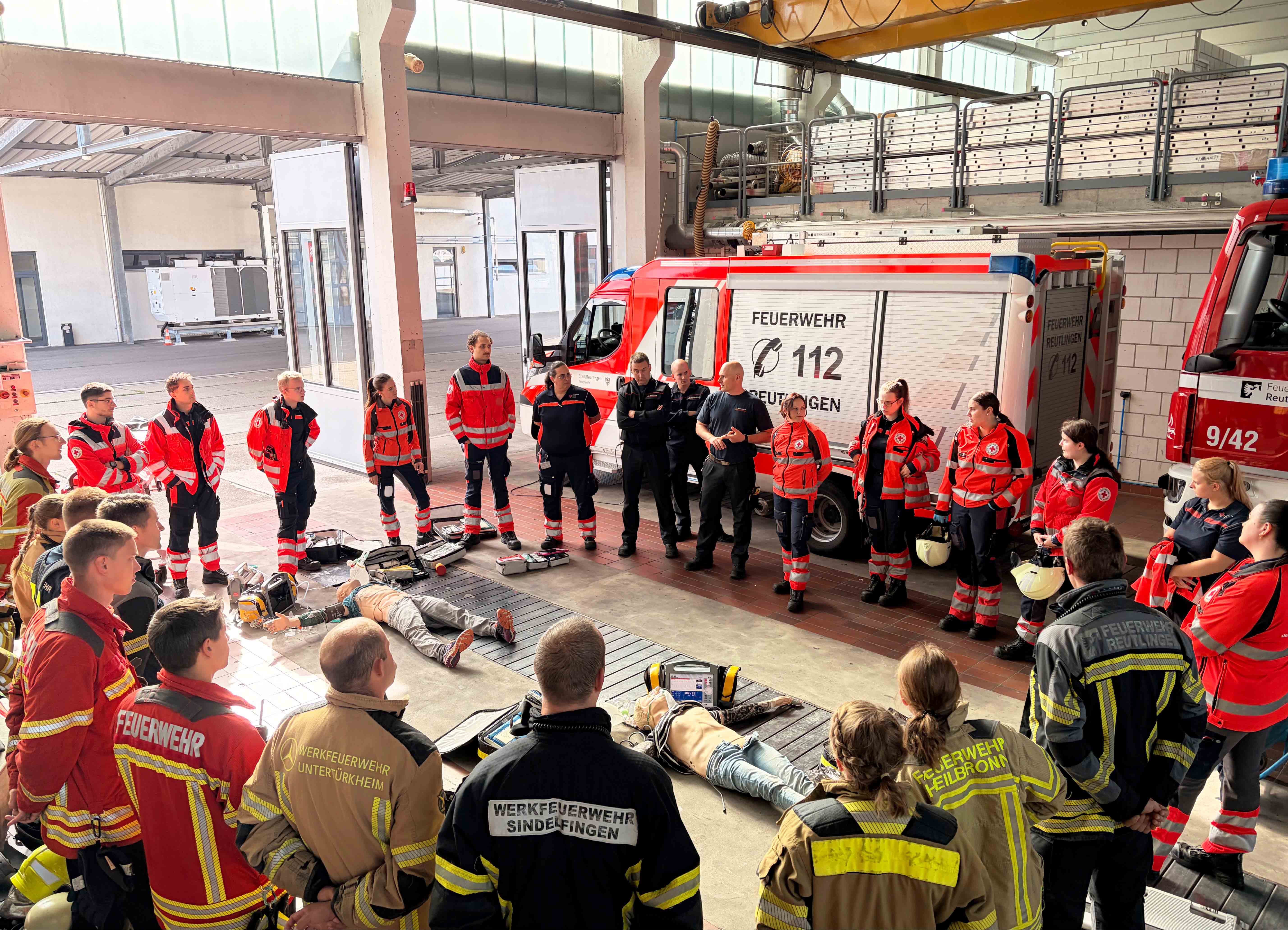 Bild: Gemeinsame Besprechung alle Teilnehmenden in der Fahrzeughalle der Feuerwehr