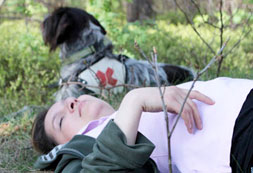 Verletzte Frau im Gras mit Rettungshund