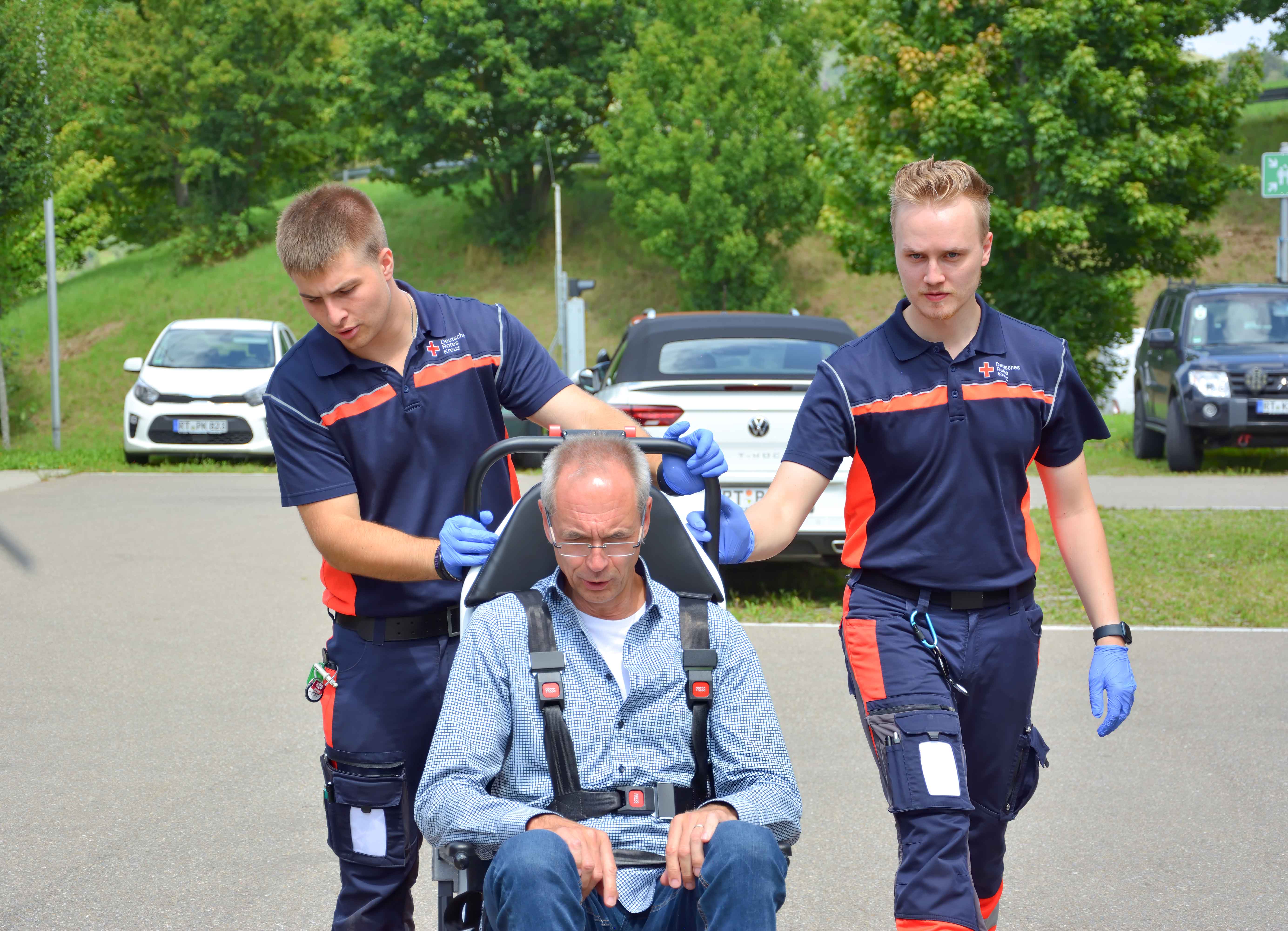 Zwei Sanitäter versorgen einen Patienten im Transportstuhl