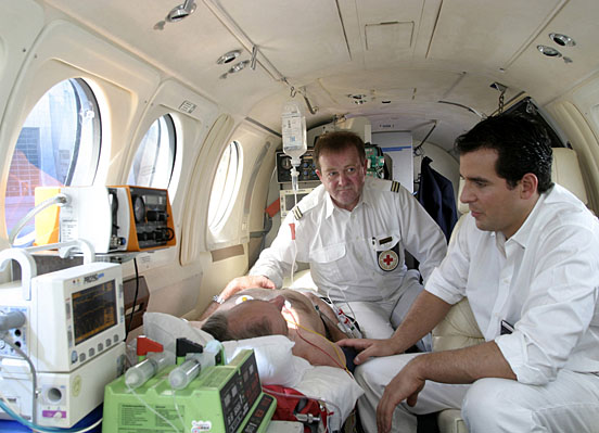 Foto: Zwei DRK-Sanitäter versorgen einen Patienten im Flugzeug.